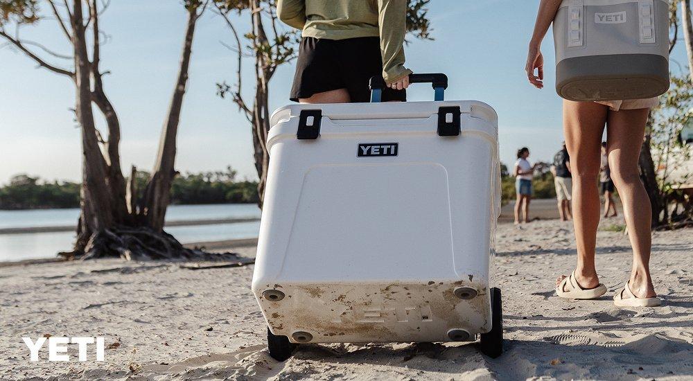 a lady pulling a yeti cooler on the beach